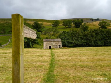 The sign says, "Great Rampshone cowhouse. To protect the meadow crop please walk to and from the barn in single file."