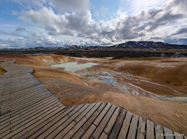 Another angle of the colored soil, boiling water, with one of the volcanoes of the Krafla volcanic region in the background