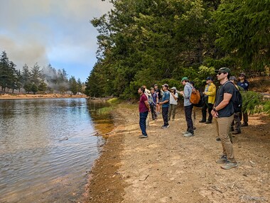 Our group listens to Carl talk about how indigenous peoples used fire to manage the landscape while the fire across the lake roared.